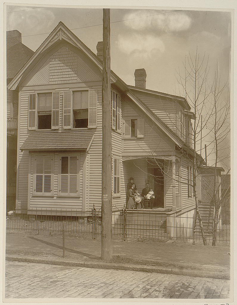 An African American family posed on the porch of a Georgia house around 1899 or 1900.