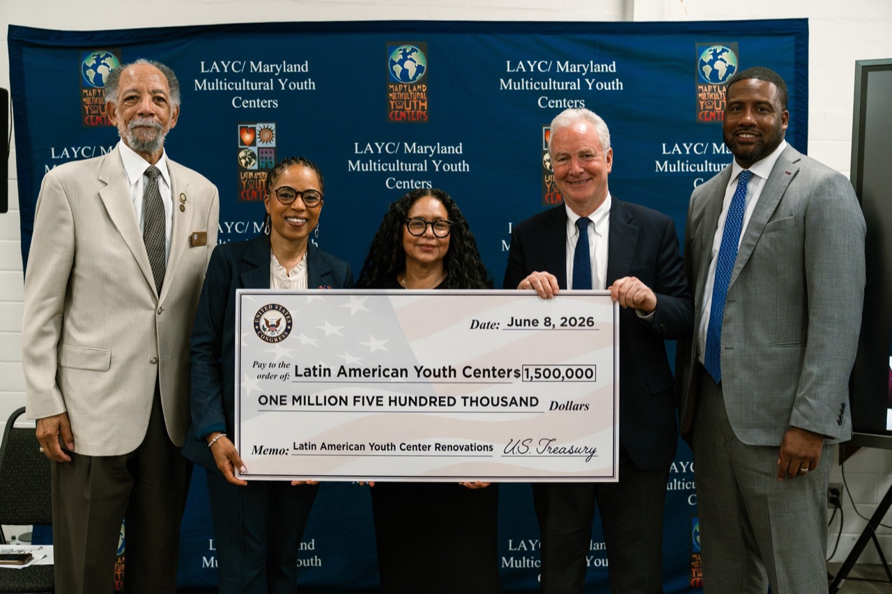 Group photograph at a Latin American Youth Center event with public officials holding a ceremonial funding check.