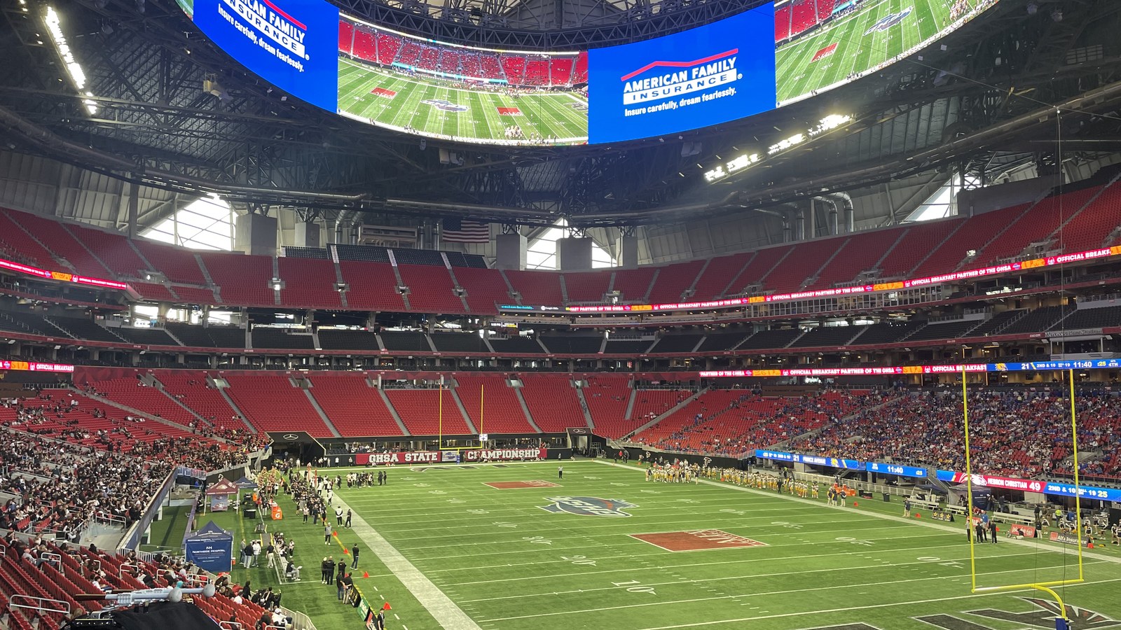 Interior view of Mercedes-Benz Stadium in Atlanta during a 2024 football championship game, showing the field, seating bowl, video board, and stadium roof.
